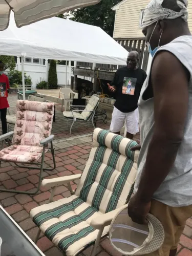 Two men loading donated garden chairs for shipping, outside a house in New Jersey.