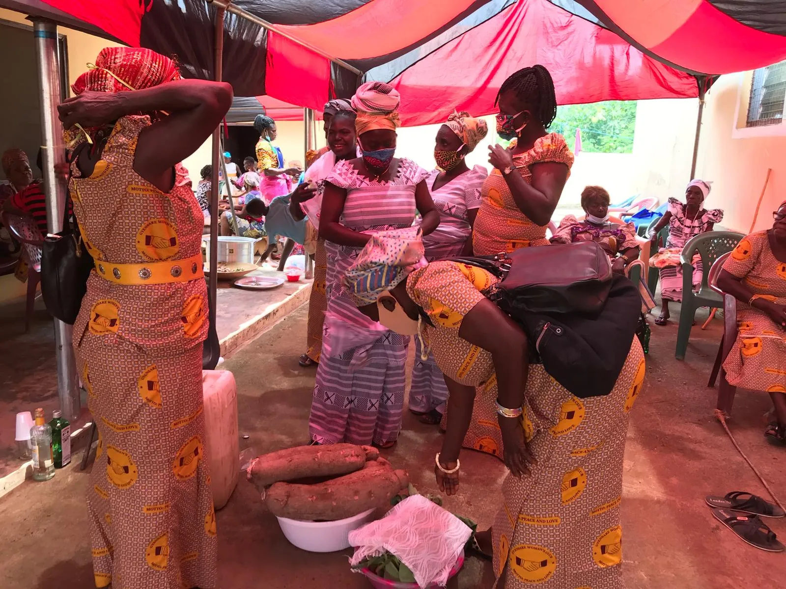 Members of the Gyensare Women’s Club, in matching cloth printed with the motto “peace and love”, preparing yams under a canopy.